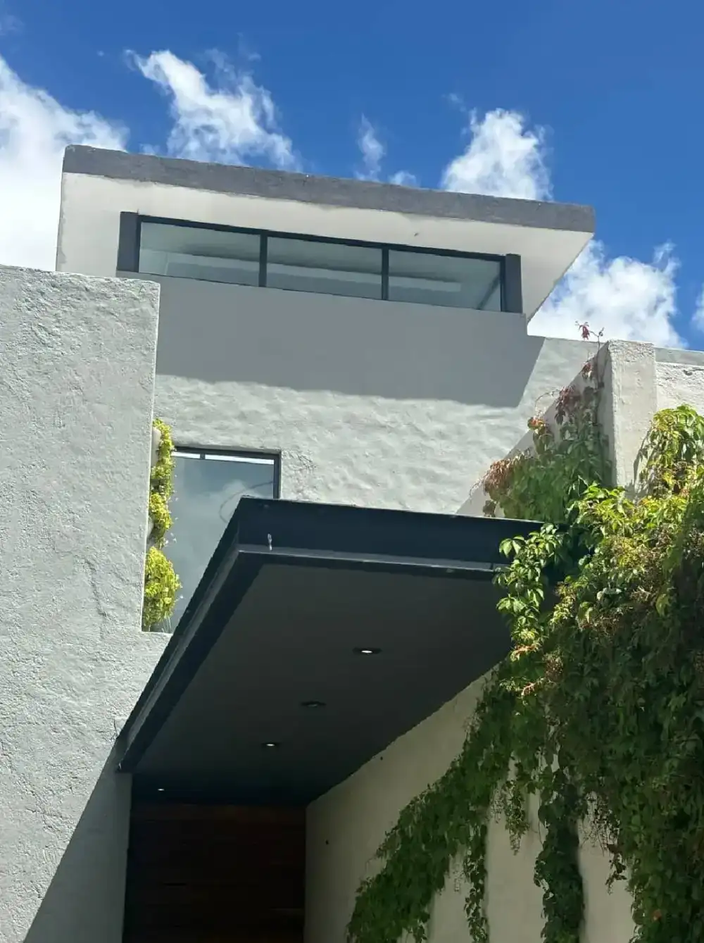 Vista ascendente de la fachada de Casa Sagrado Corazón con voladizo y enredadera, El Campanario, Querétaro