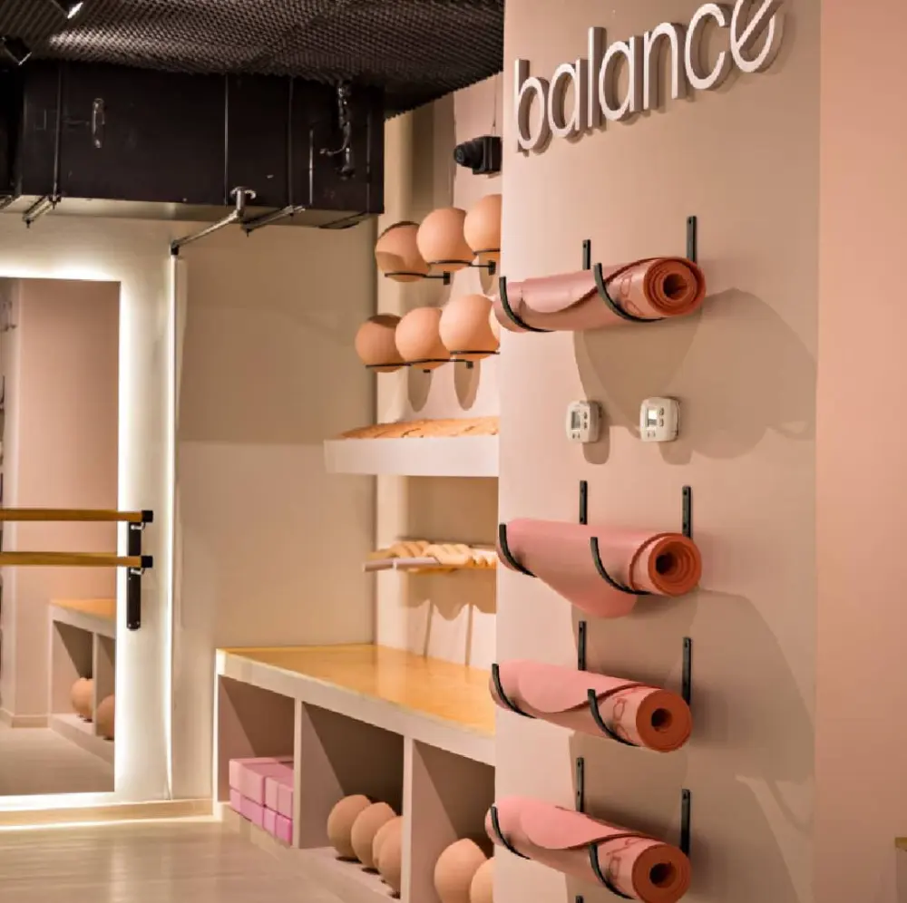 Pasillo de acceso a Balance con letrero de la marca y tapetes de yoga en repisas, adecuación de local comercial en Querétaro