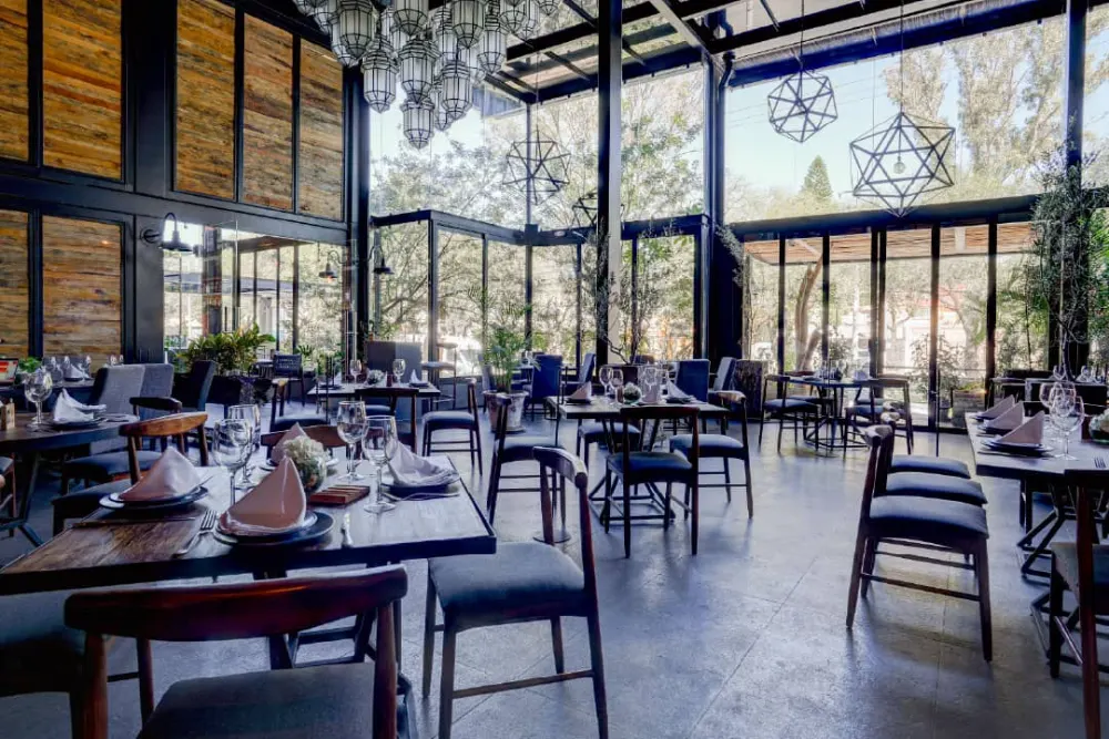 Comedor con grandes ventanales hacia el jardín exterior, arquitectura del restaurante Don Vito en Querétaro