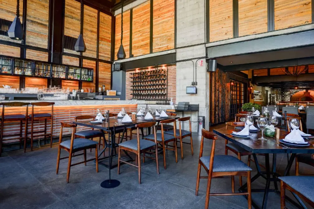 Barra y comedor con techos de madera y tinajero de vinos en la construcción del local gastronómico Don Vito en Querétaro