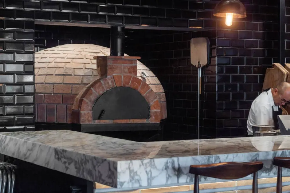 Horno italiano de ladrillo junto a barra de mármol durante la creación del restaurante Don Vito en Querétaro