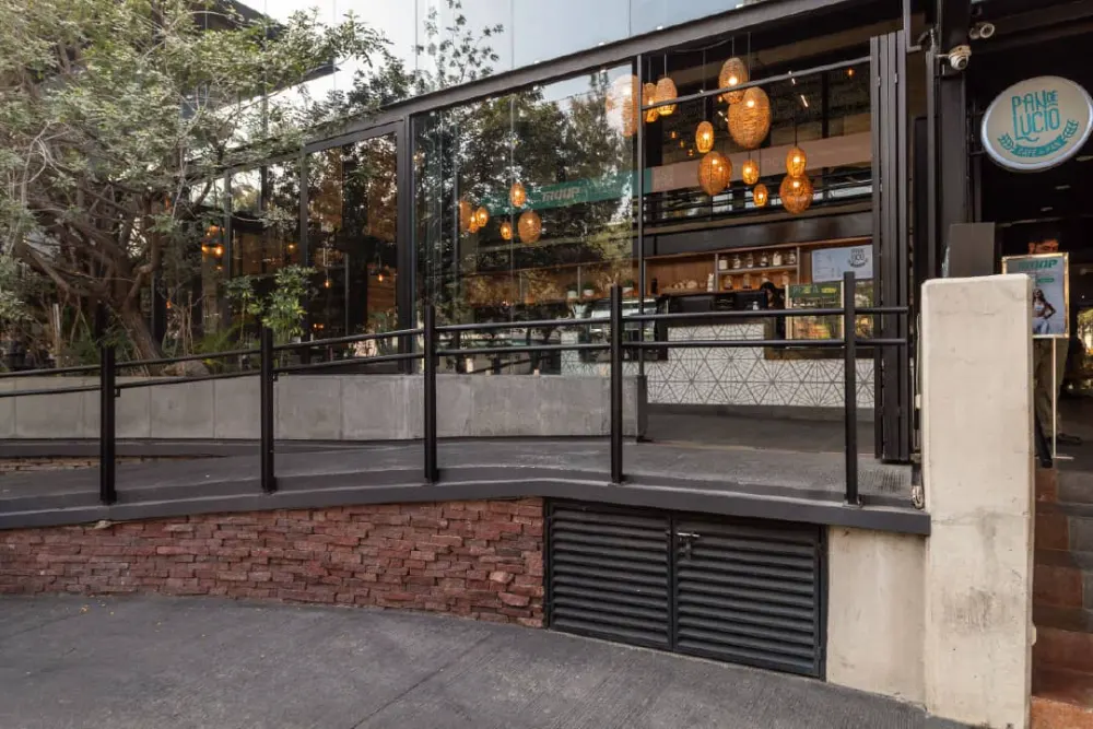 Fachada de acceso a Pan de Lucio con letrero de la marca y candiles colgantes en Querétaro