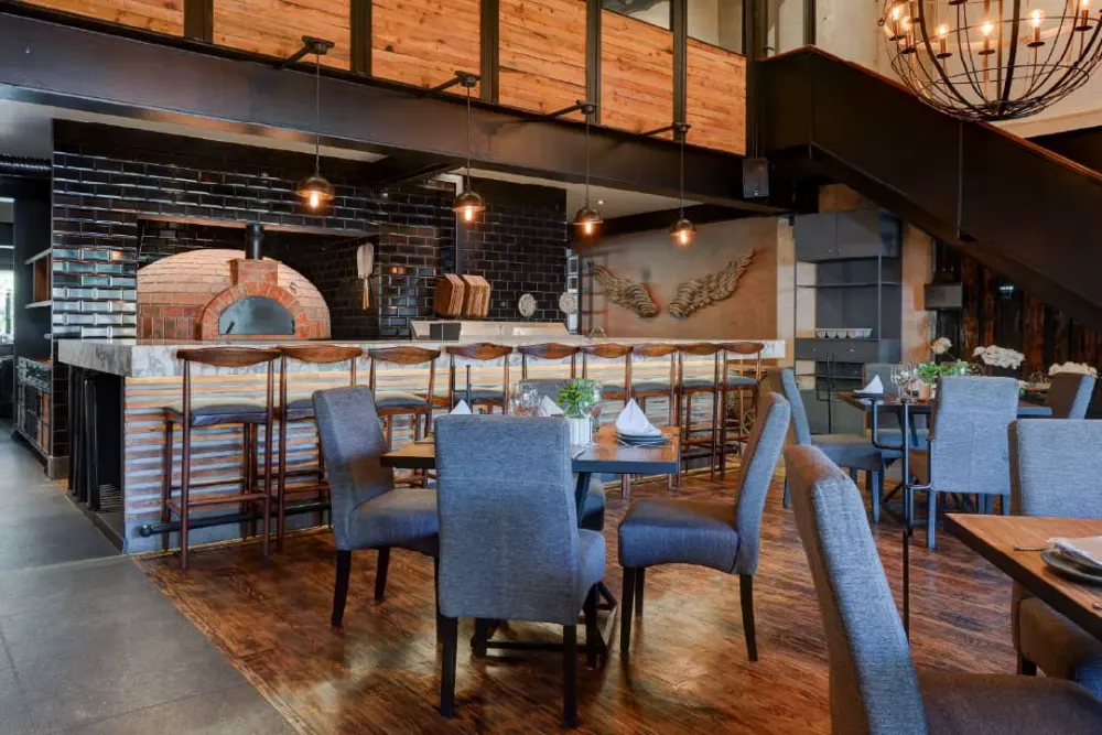 Barra con horno italiano y comedor de mesas de madera en el proyecto del restaurante Don Vito en Querétaro