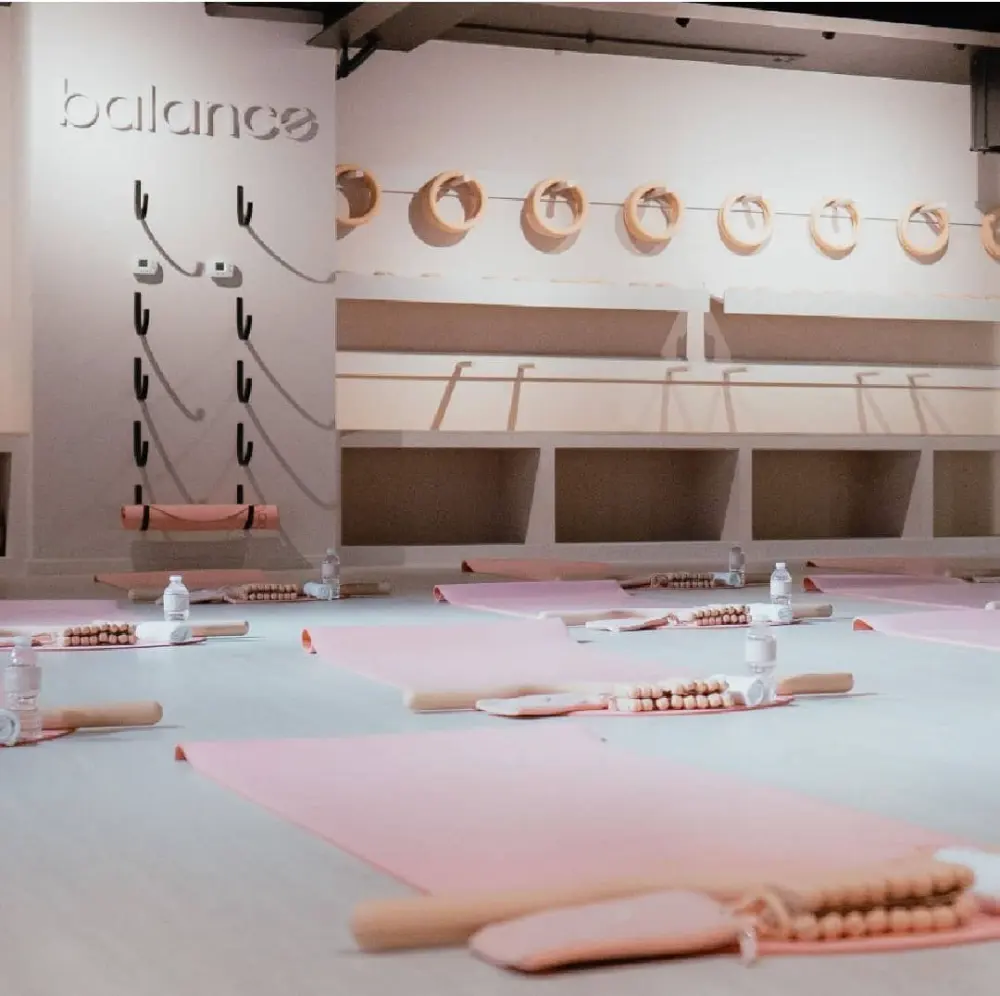 Salón con tapetes rosas, botellas de agua y accesorios de práctica tras la remodelación del local comercial Balance