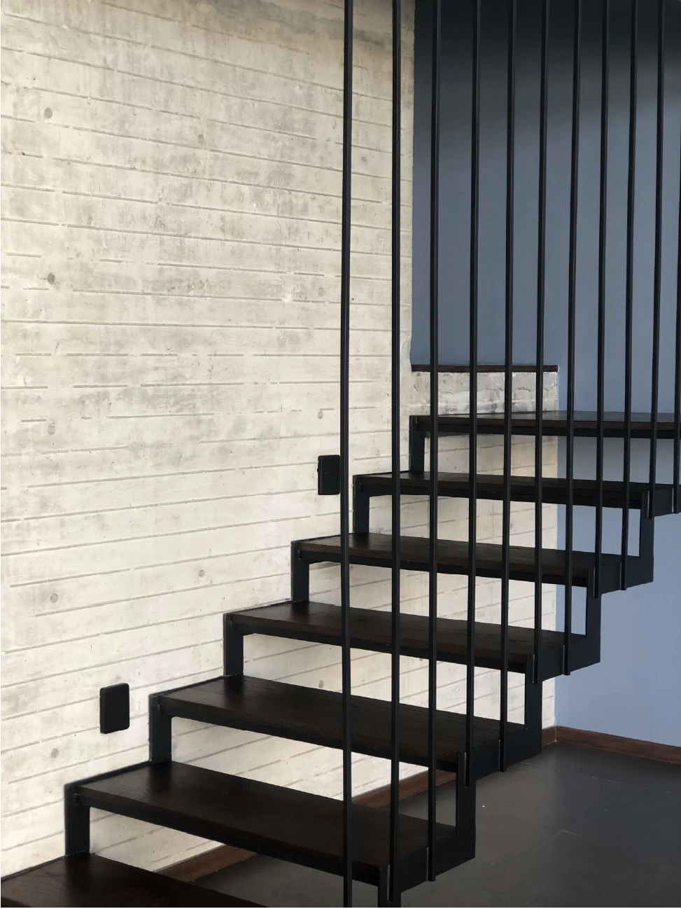 Escalera volada de acero y madera junto a muro de concreto aparente en Casa Moro, Juriquilla