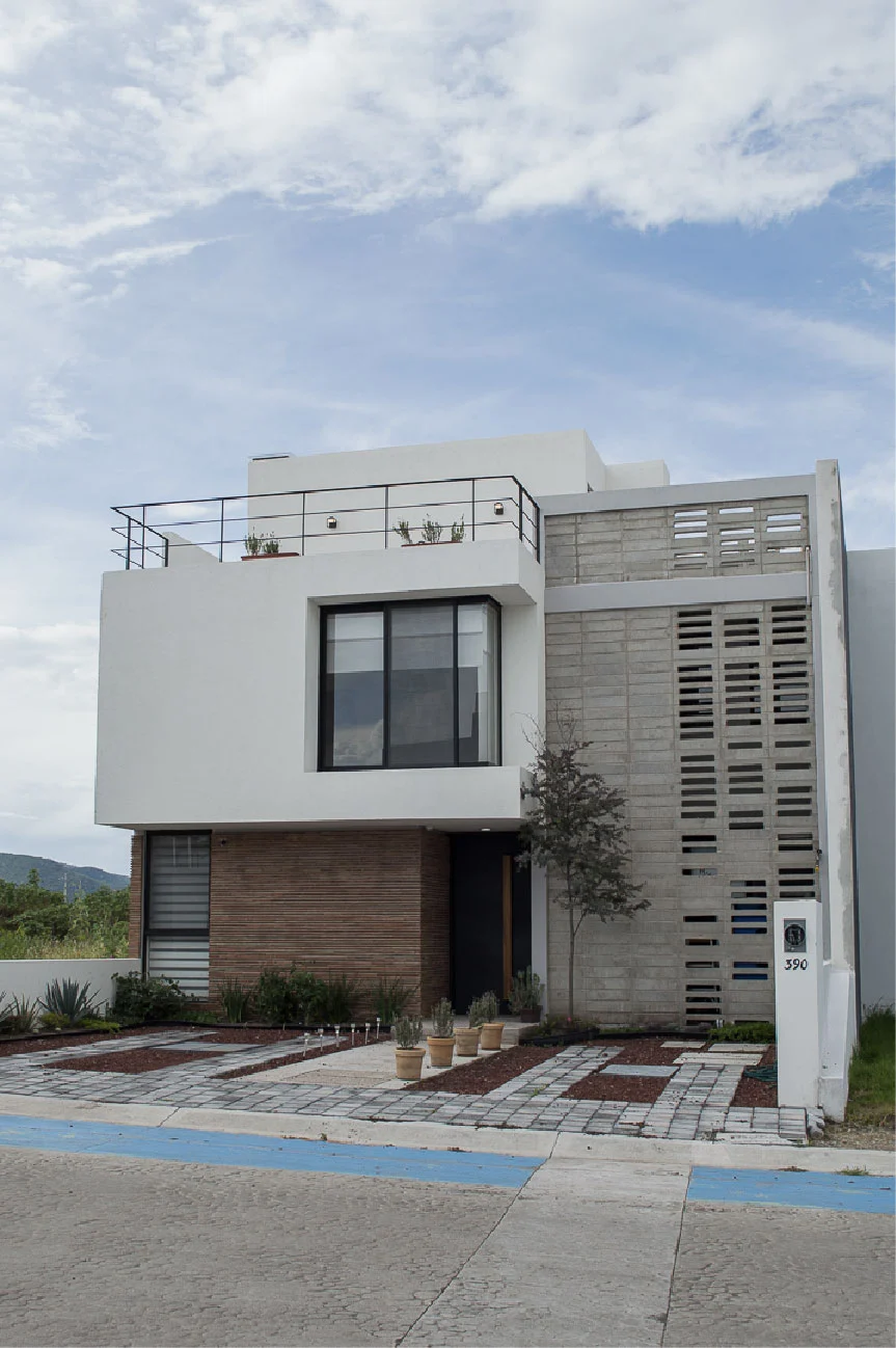 Fachada terminada de una casa con volumen blanco, ladrillo y celosía de concreto, resultado de un anteproyecto en Querétaro