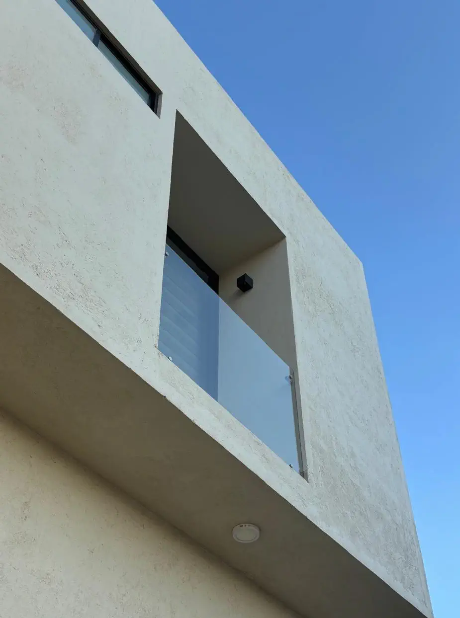 Balcón con barandal de cristal en un nicho de la fachada de Casa Paseo en Juriquilla, Querétaro