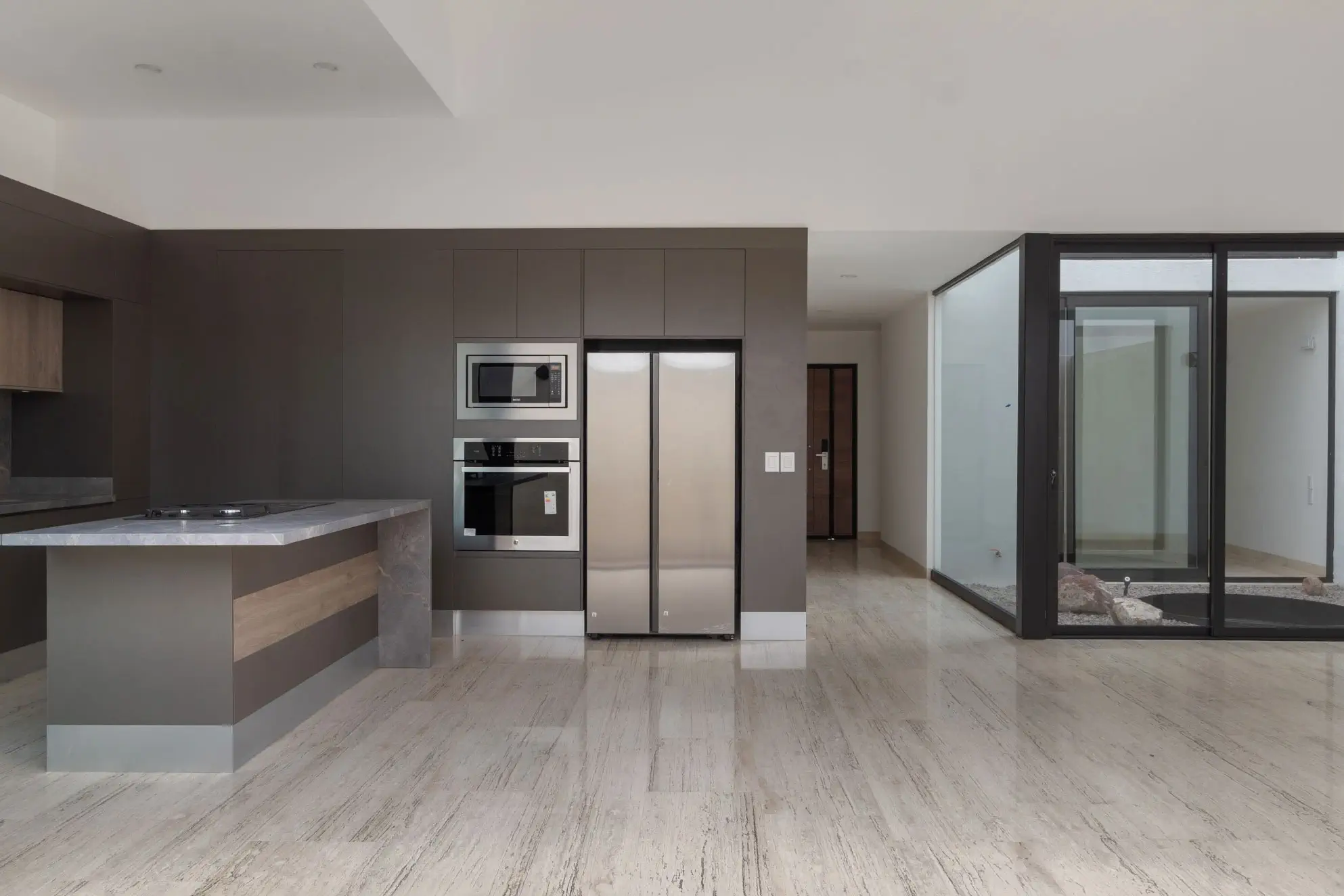 Cocina con isla de granito, refrigerador y patio interior acristalado en Casa Paseo, Querétaro
