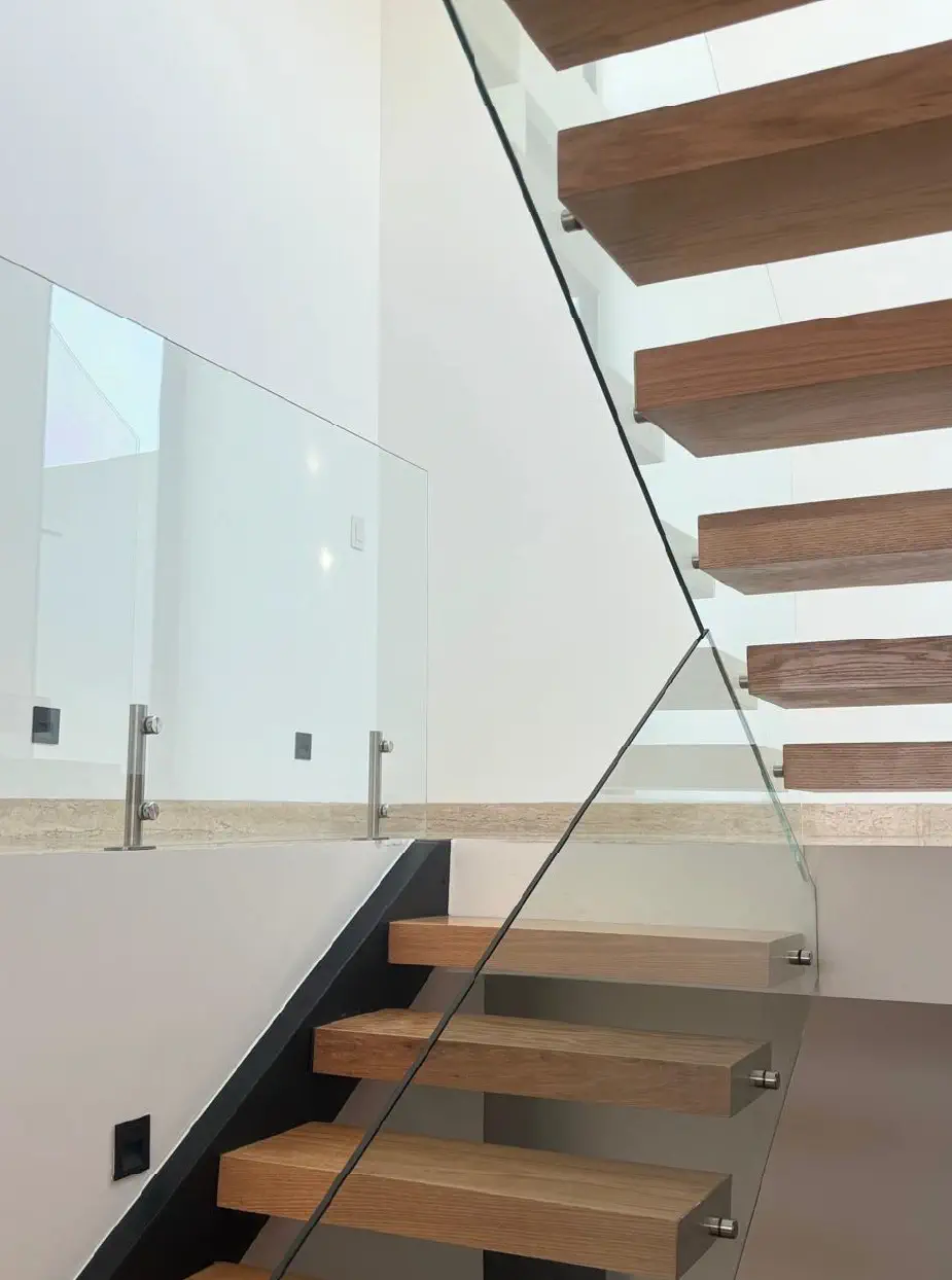 Escalera flotante de madera con barandal de cristal y herrajes de acero en Casa Paseo
