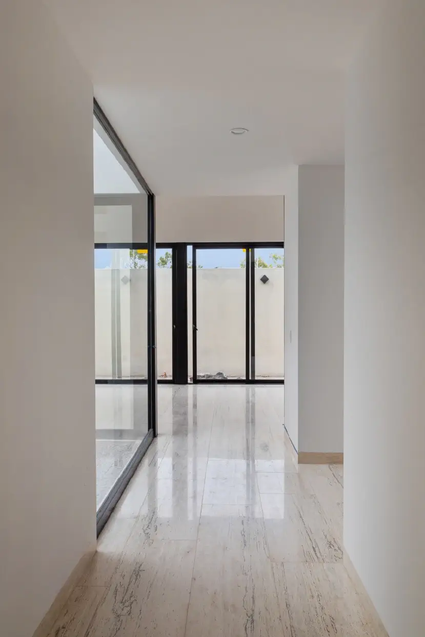 Pasillo de piso de travertino que conecta el vestíbulo con la sala y el patio de Casa Paseo