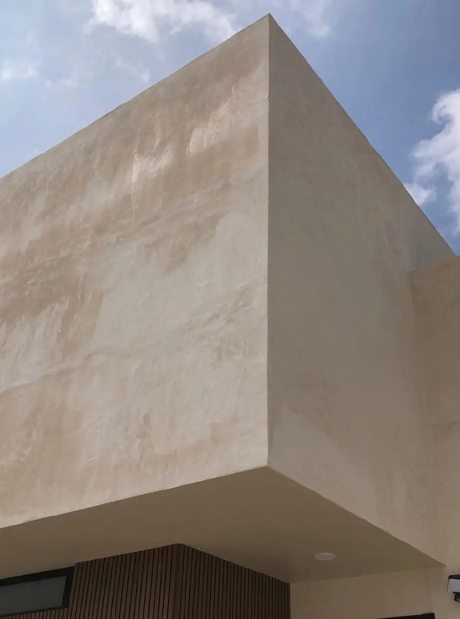 Esquina de un volumen en voladizo con acabado texturizado y recubrimiento de madera en una casa de Juriquilla