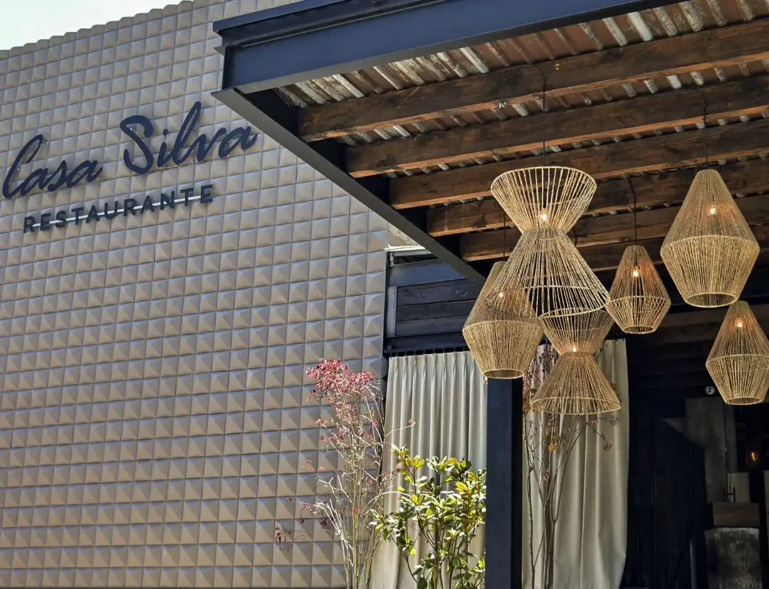 Comedor de Casa Silva con muros de madera natural y ventanales de piso a techo hacia la vegetación