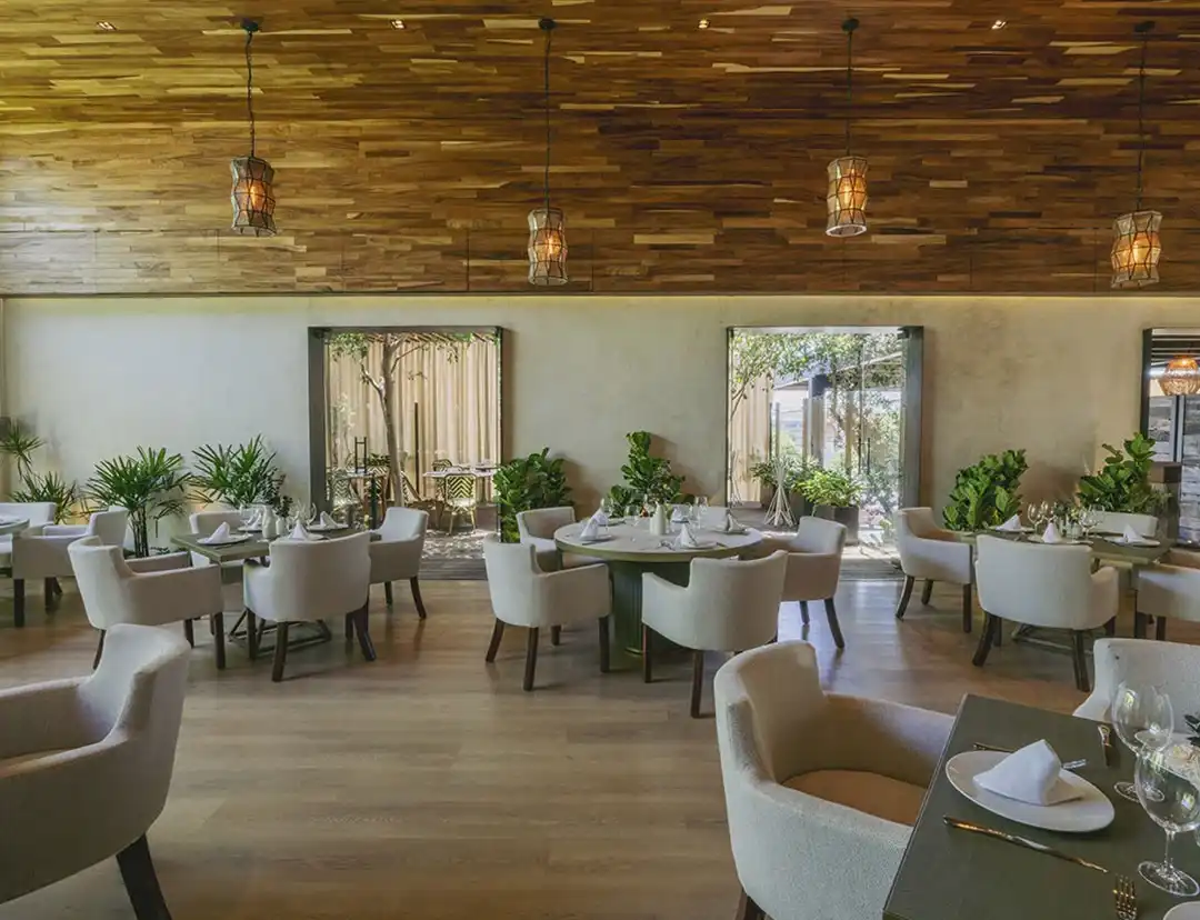 Banqueta curva con ventanal y plantas en el comedor de Casa Silva