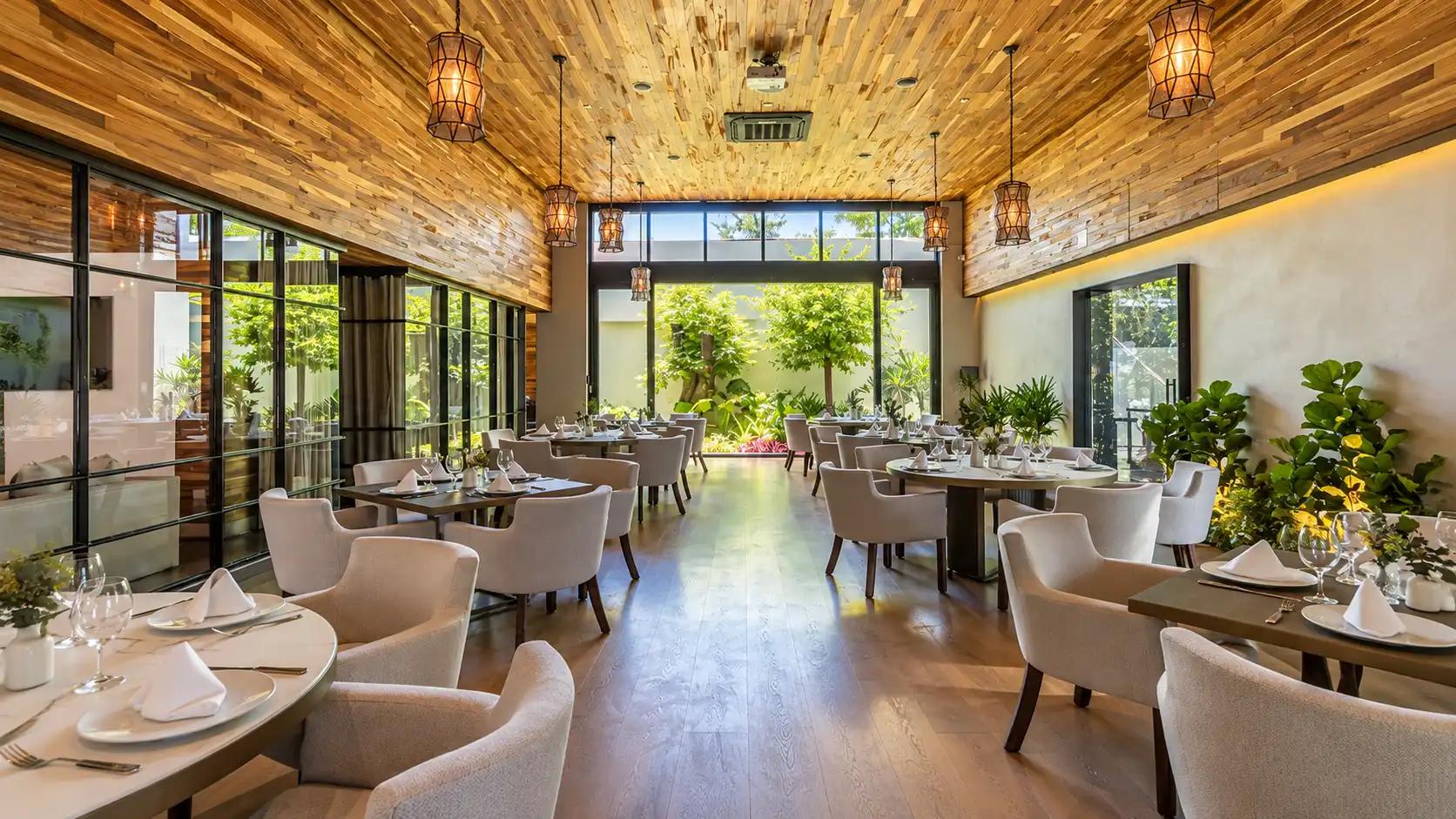 Casa Silva — salón de restaurante con jardín interior, Querétaro Salón de Casa Silva con techo de madera, sillones tapizados y ventanales hacia un jardín interior en Querétaro
