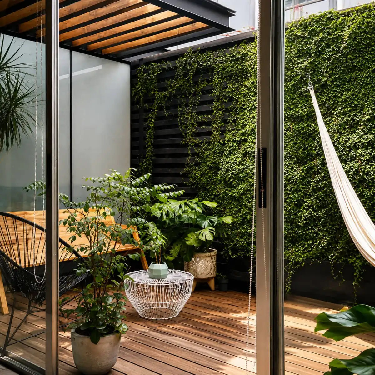 Comedor con mesa redonda de madera y vista al jardín interior lleno de vegetación en Departamento 2018