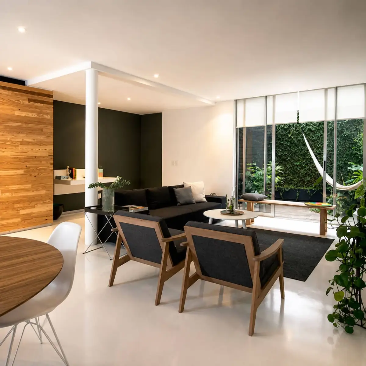 Sala de estar con sofá oscuro, sillones de madera y vista al patio con hamaca en Departamento 2018