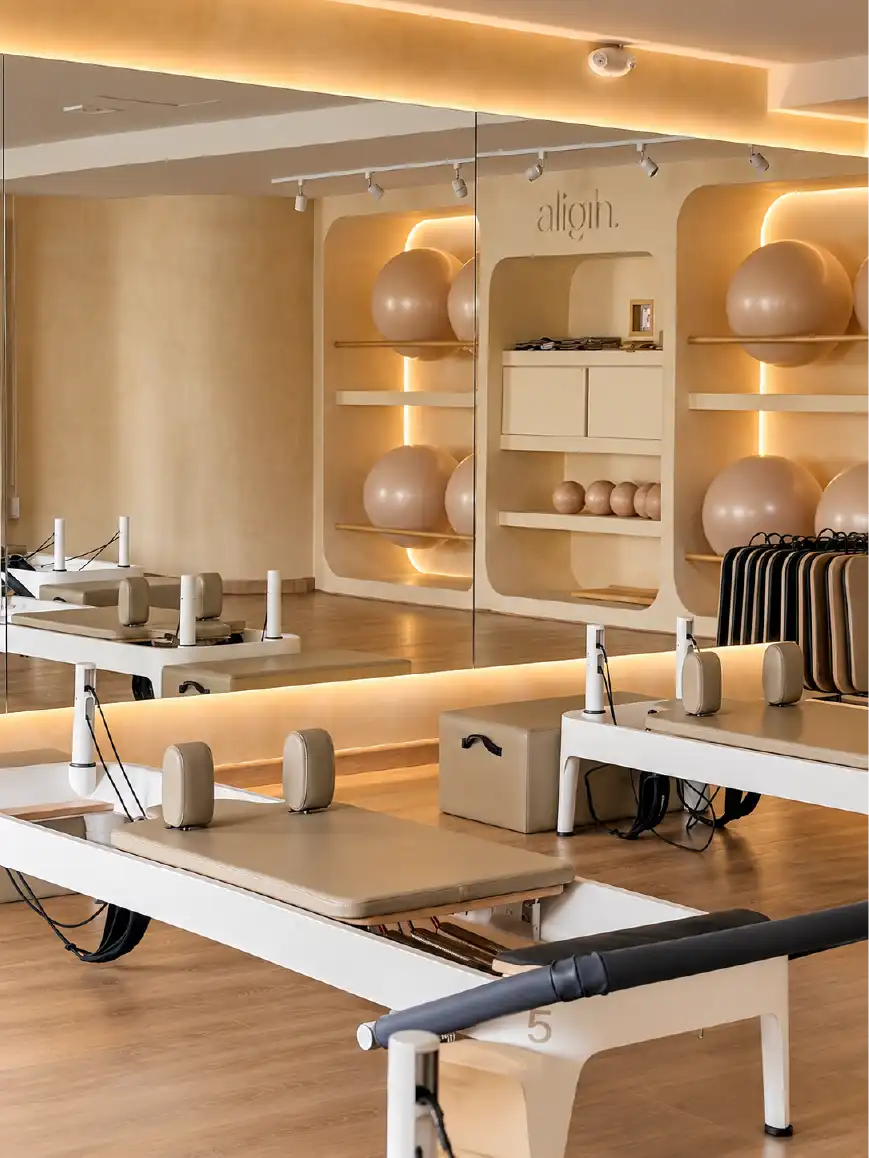Estudio de pilates reformer con muebles de madera tono pino, nichos para pelotas y espejos en Querétaro