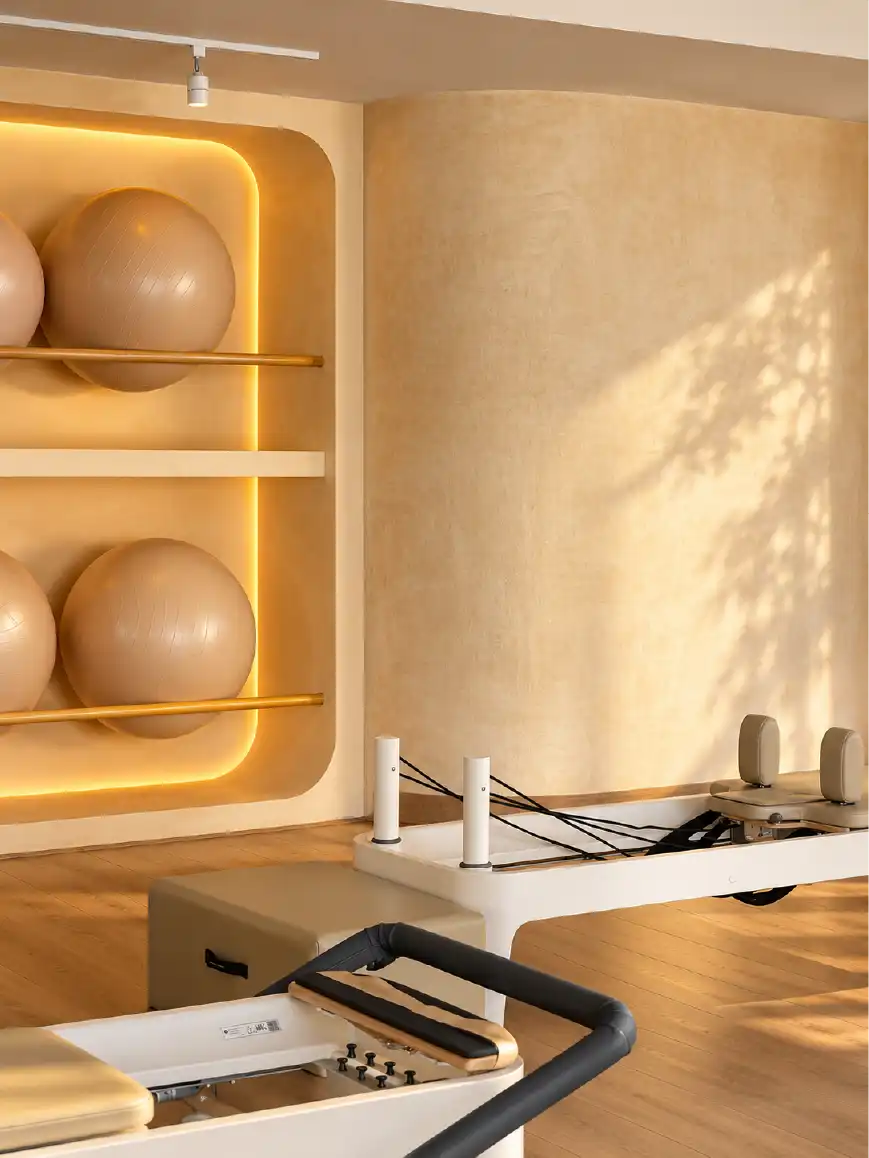Nicho iluminado para pelotas de pilates, muro curvo de chukum y reformer en el diseño interior del estudio Align en Querétaro