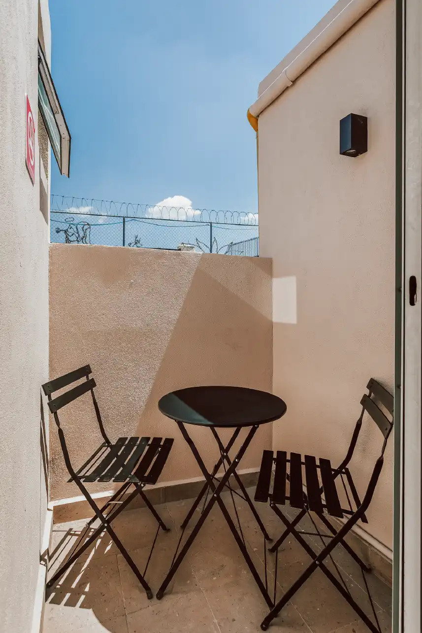 Balcón privado con mesa y sillas plegables en departamento de renta vacacional en Querétaro