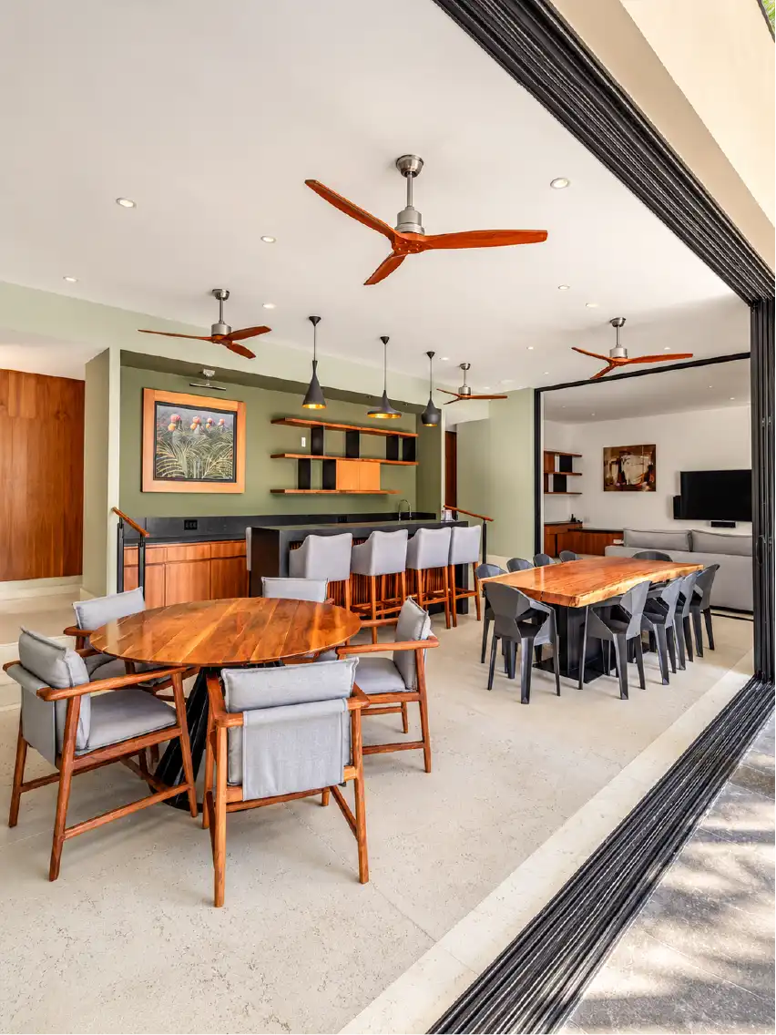 Comedor y bar con mobiliario de madera a la medida, ventiladores y puertas corredizas en una casa de Querétaro
