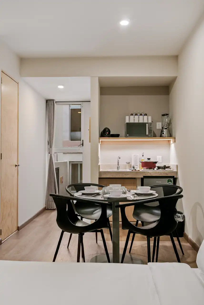 Comedor redondo y cocineta con repisa iluminada en estudio para Airbnb en Querétaro