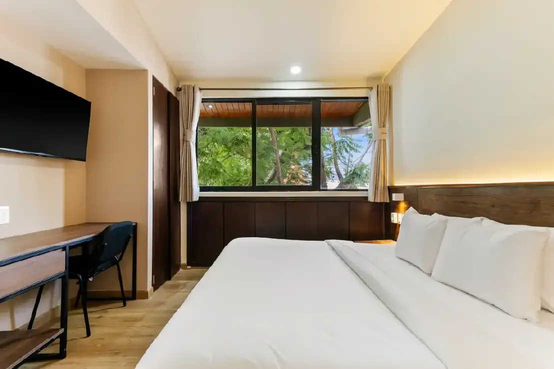 Habitación con cama king, escritorio y ventana hacia árboles en departamento de renta vacacional en Querétaro