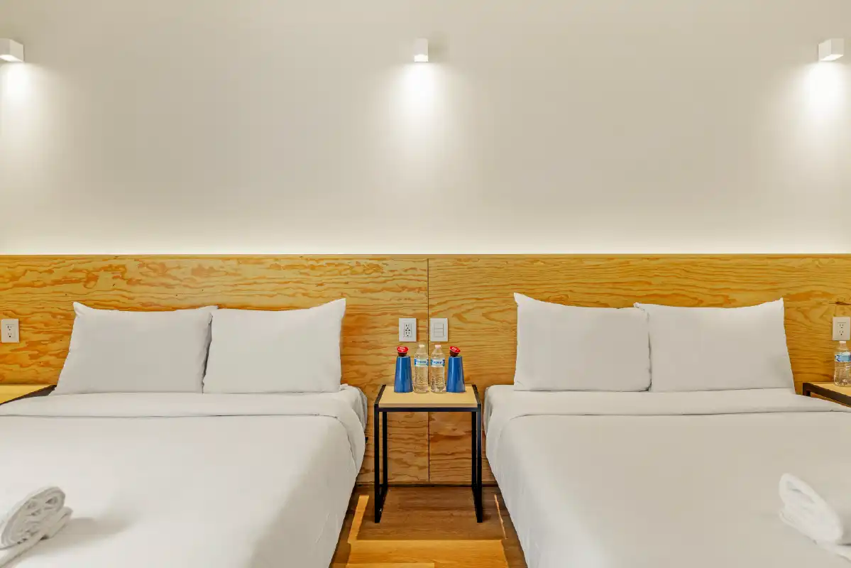 Habitación con dos camas y cabecera de madera contrachapada en departamento de renta vacacional
