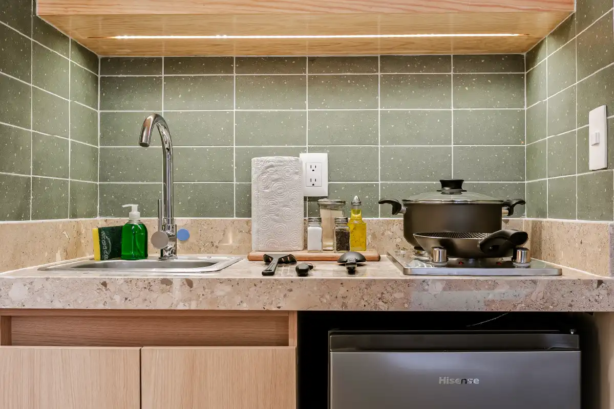 Cocineta con azulejo verde, tarja y frigobar en departamento remodelado para renta