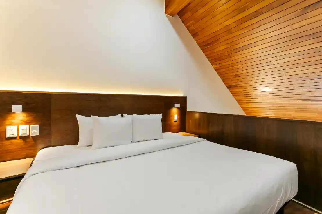 Recámara con plafón inclinado de madera y cabecera iluminada en propiedad Homi Rent en Querétaro