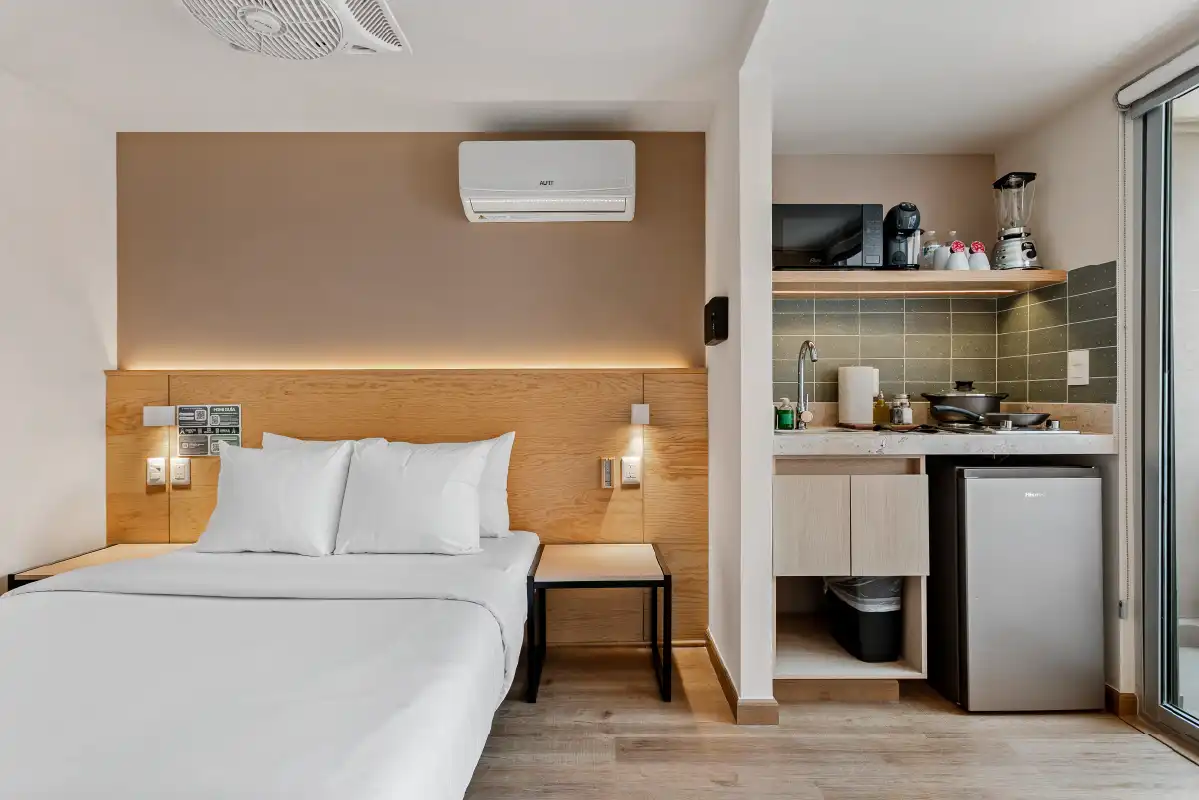 Recámara con cocineta integrada y cabecera de madera en departamento remodelado para Airbnb