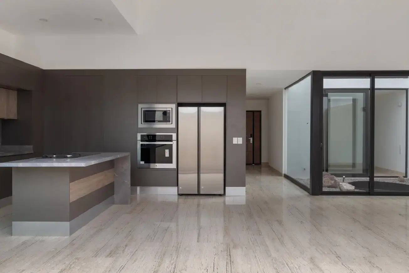 Cocina con isla de piedra, línea de electrodomésticos y patio interior acristalado en residencia de Juriquilla, Querétaro