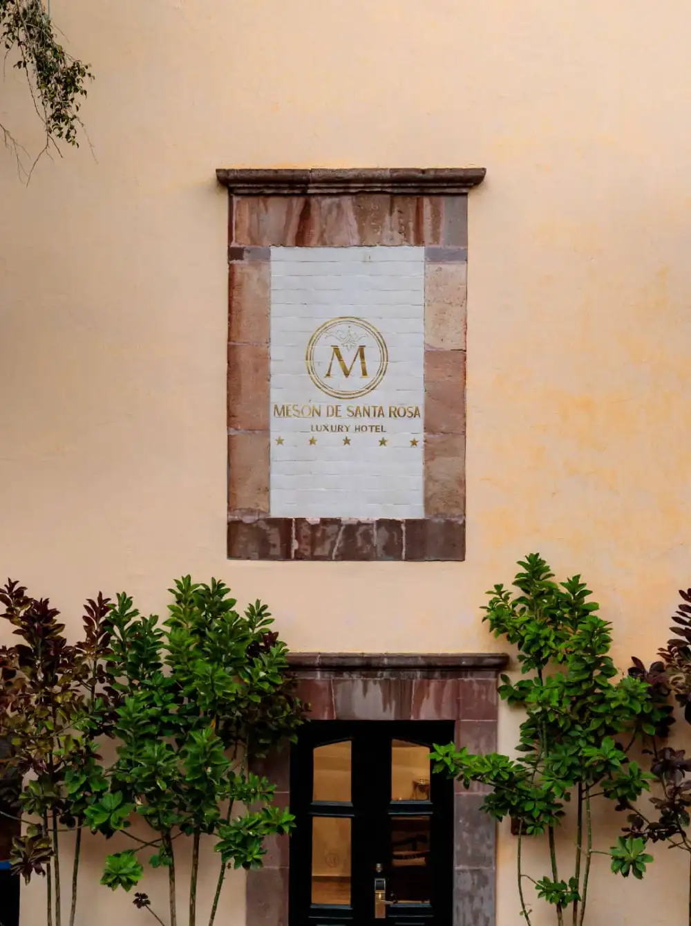 Letrero dorado del Mesón de Santa Rosa Luxury Hotel sobre muro de cantera