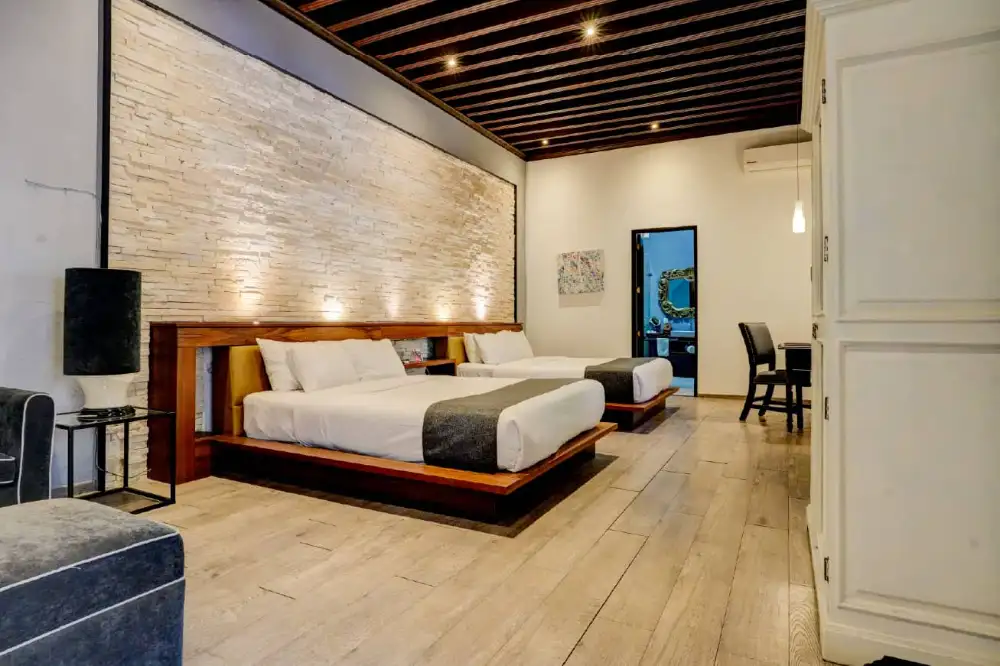 Habitación moderna con piso de madera y muro de piedra en el Mesón Santa Rosa, Querétaro