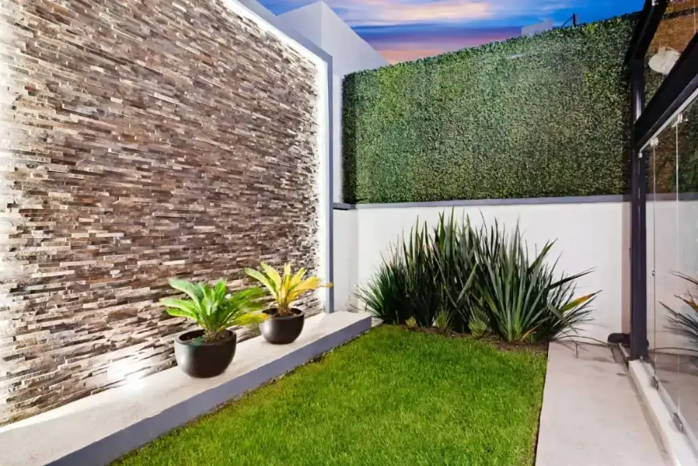 Vista de la terraza con mesa de billar, salas de exterior y muro de tabique aparente hacia el jardín