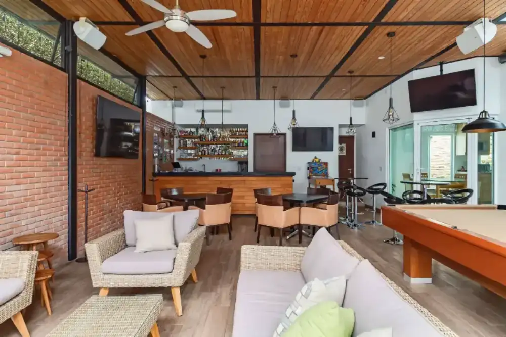 Terraza con mesa de billar, sala tejida y bar de madera vistos desde el área social