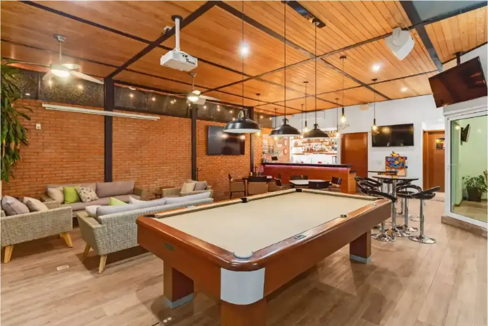 Zona de juegos con dardos, tacos de billar y decoración de letreros vintage sobre tabique